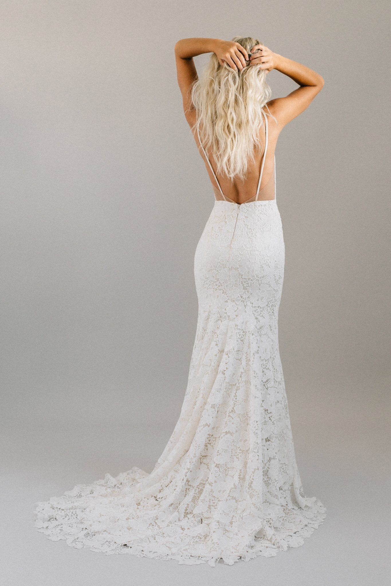 Boho backless wedding dress with bold floral lace, spaghetti straps, and a long train