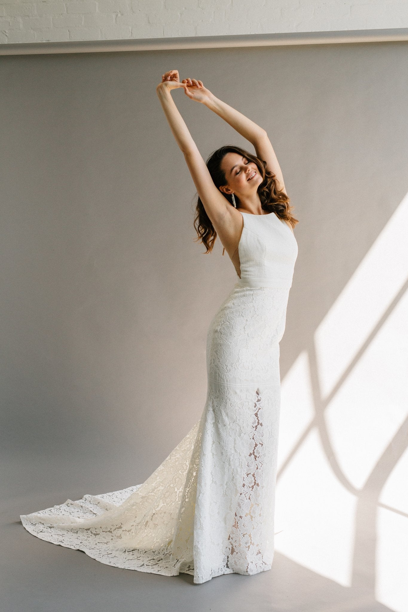 A high neck wedding dress with a low back, built-in bow, and a lace mermaid skirt with a hidden slit