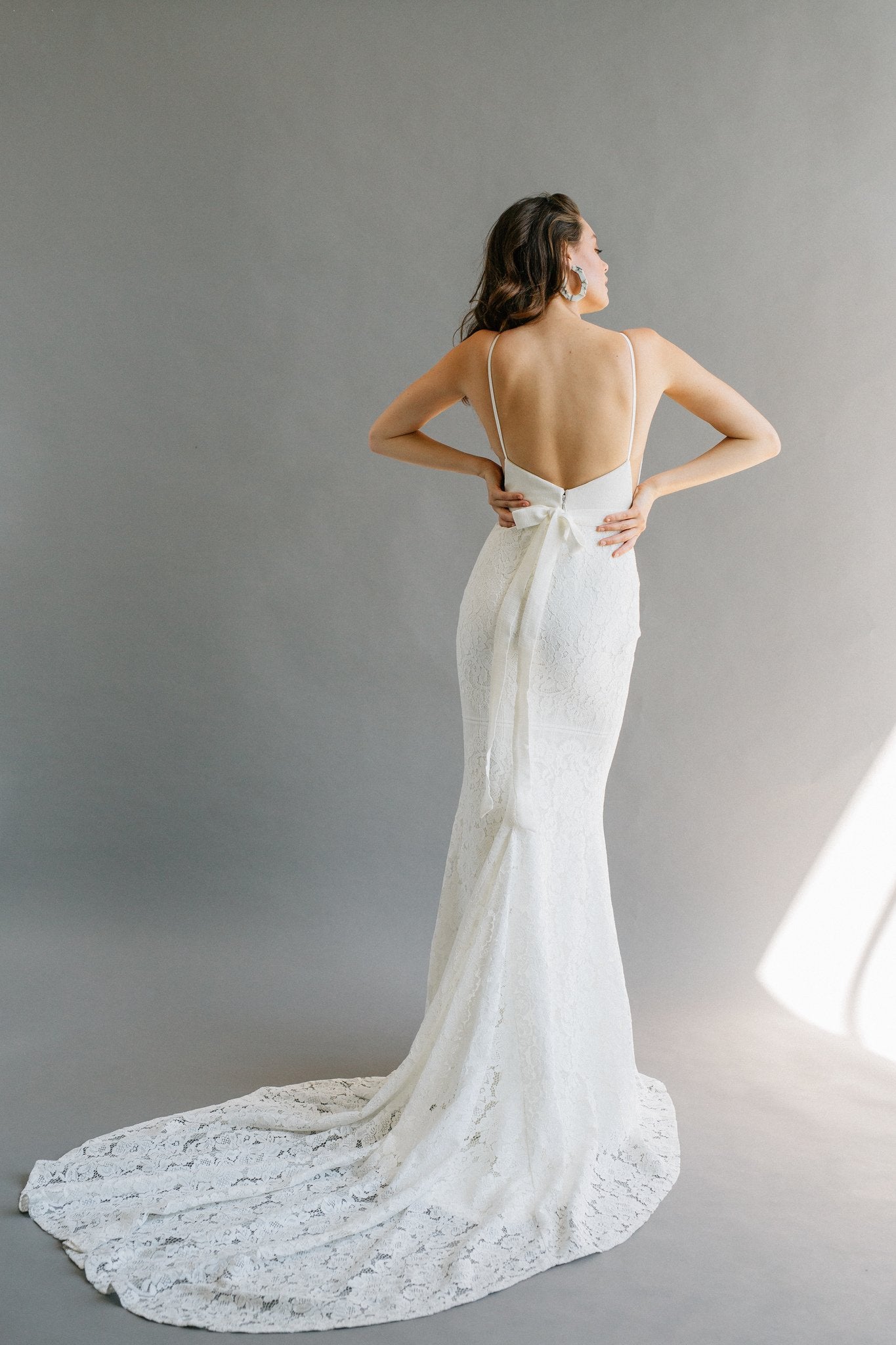 A high neck wedding dress with a low back, built-in bow, and a lace mermaid skirt with a hidden slit