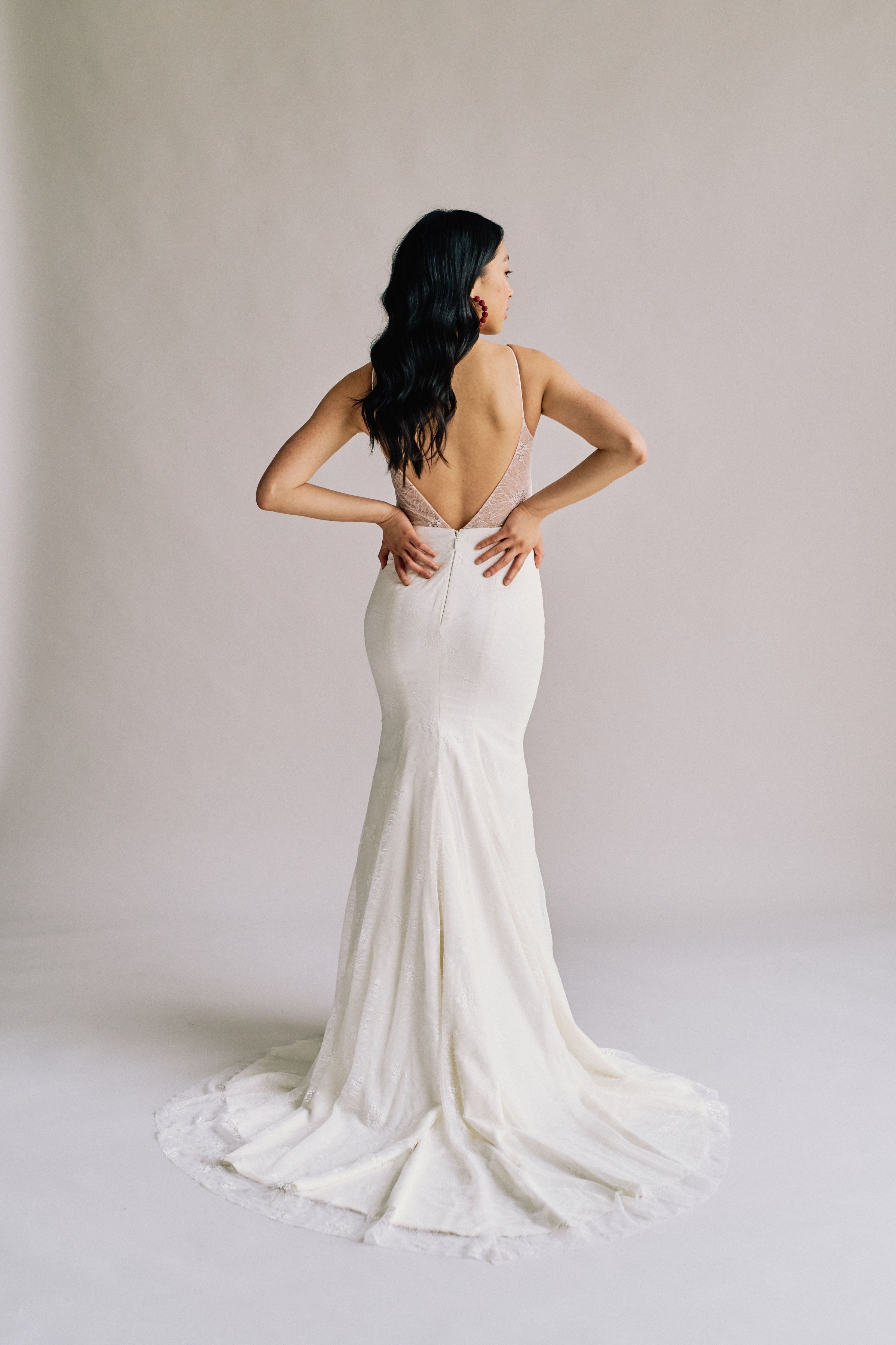 A fitted mermaid bridal gown with a delicate lace overlay, a train, and an open back