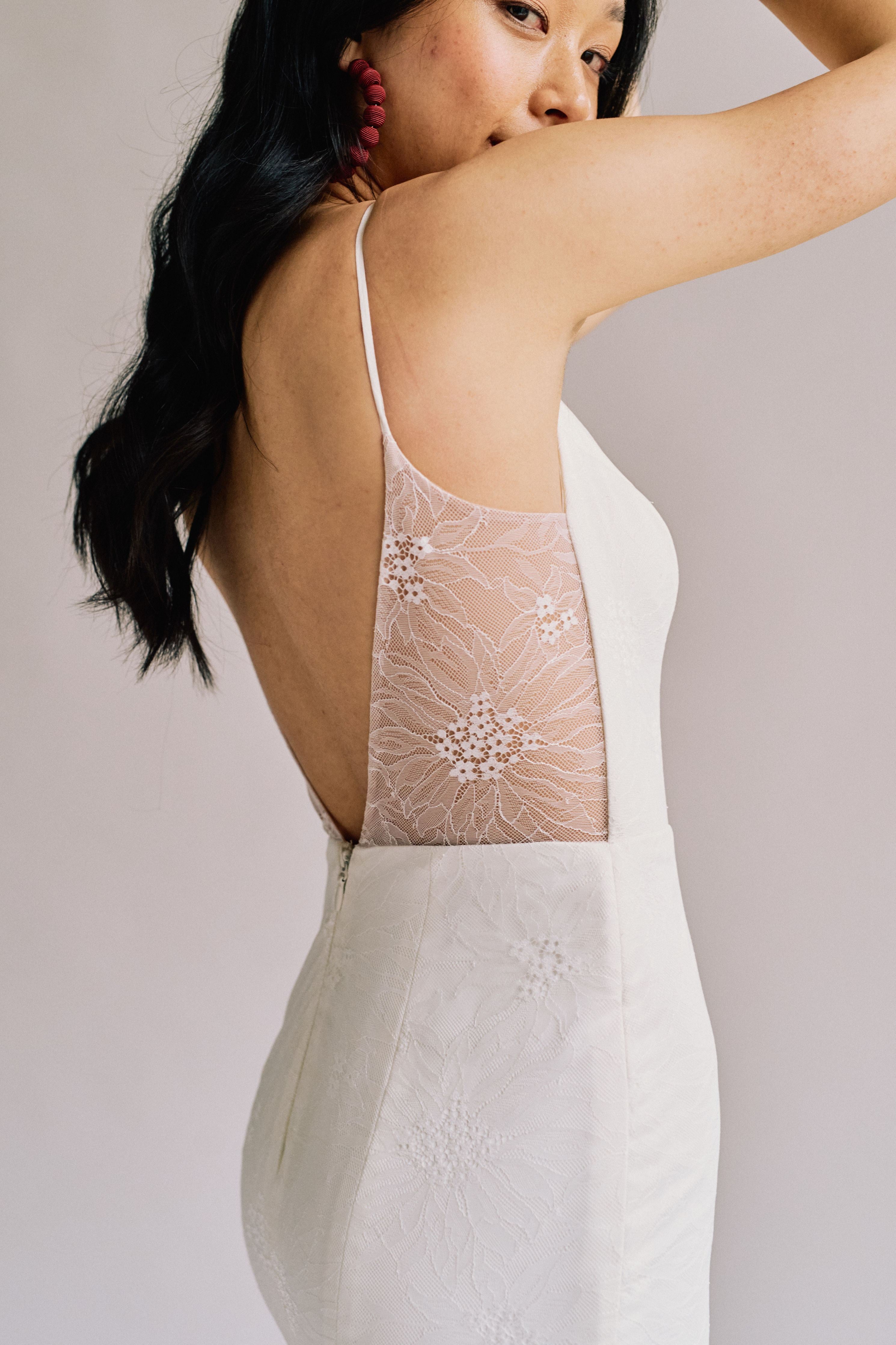 A fitted mermaid bridal gown with a delicate lace overlay, a train, and an open back