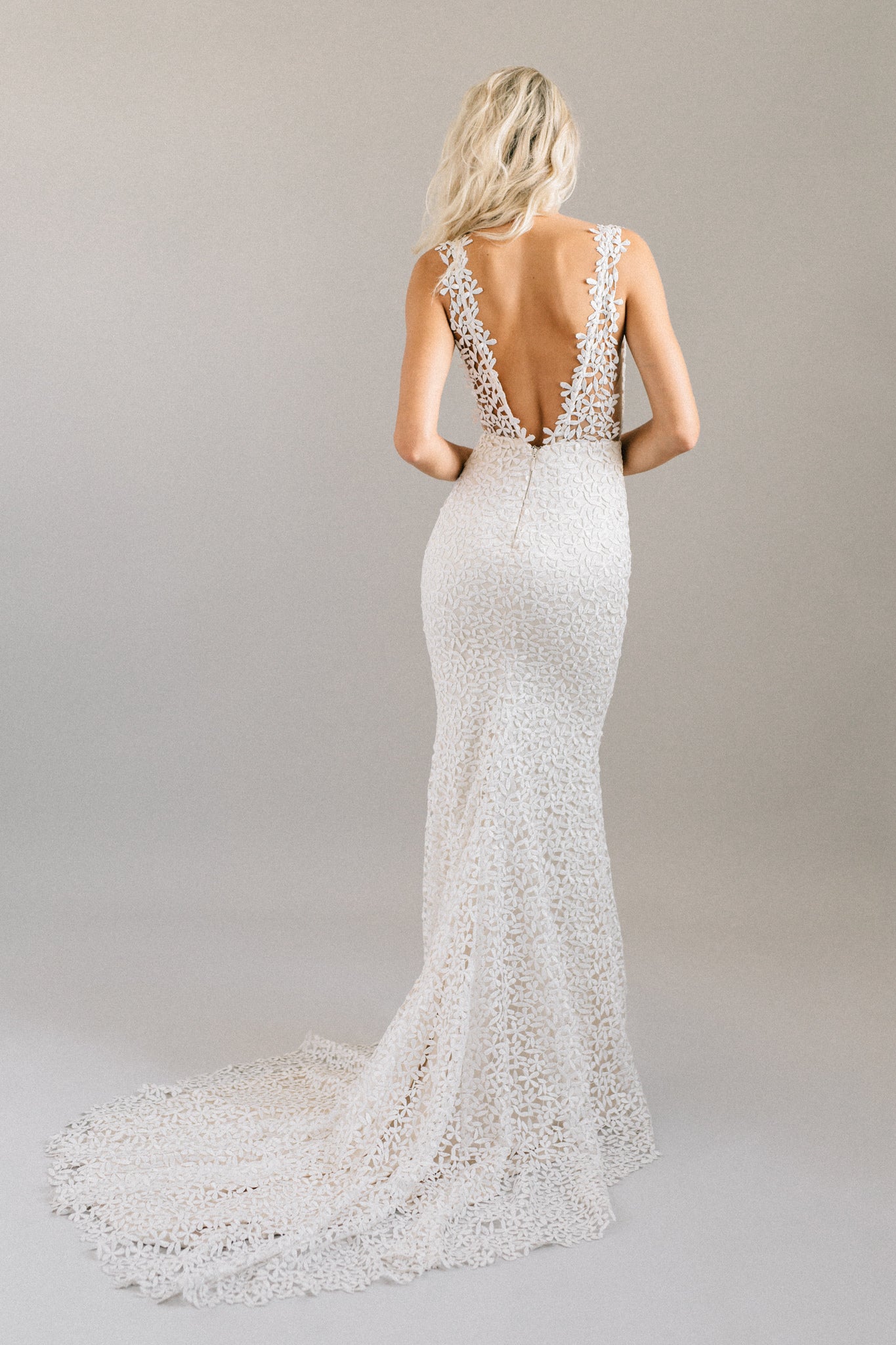 Form-fitting mermaid wedding dress with an open back, jasmine flower lace, and a dramatic pointed train